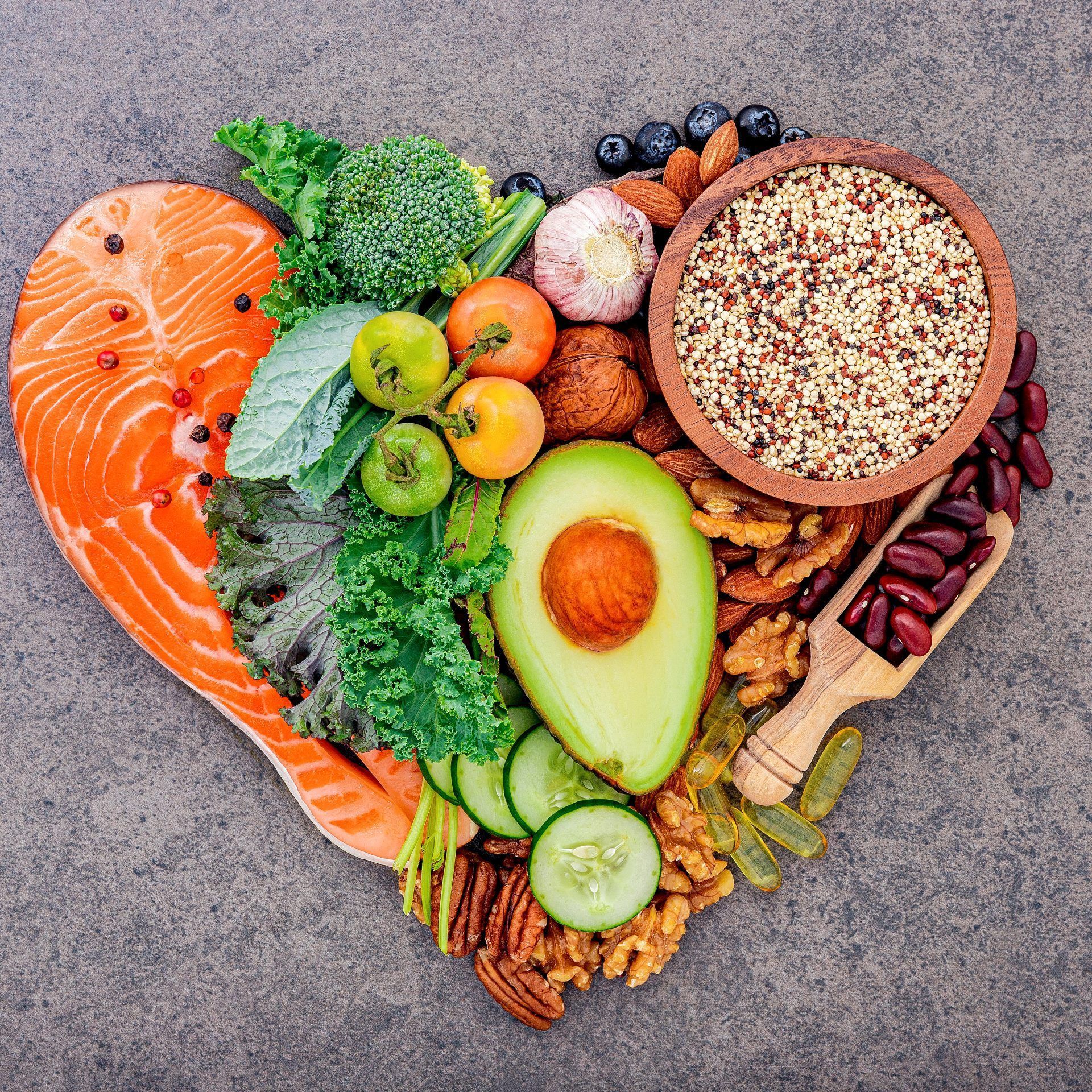 Heart shape of ketogenic low carbs diet concept. Ingredients for healthy foods selection on dark stone background.